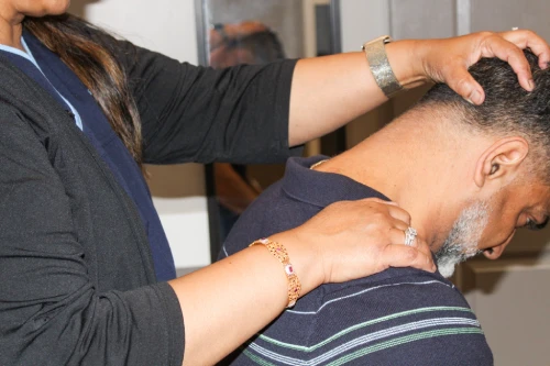 Therapist places hands on a man's neck and shoulders, providing a neck massage.
