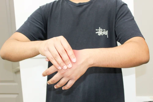 Person in a dark T-shirt rubs or massages their left wrist with the right hand.